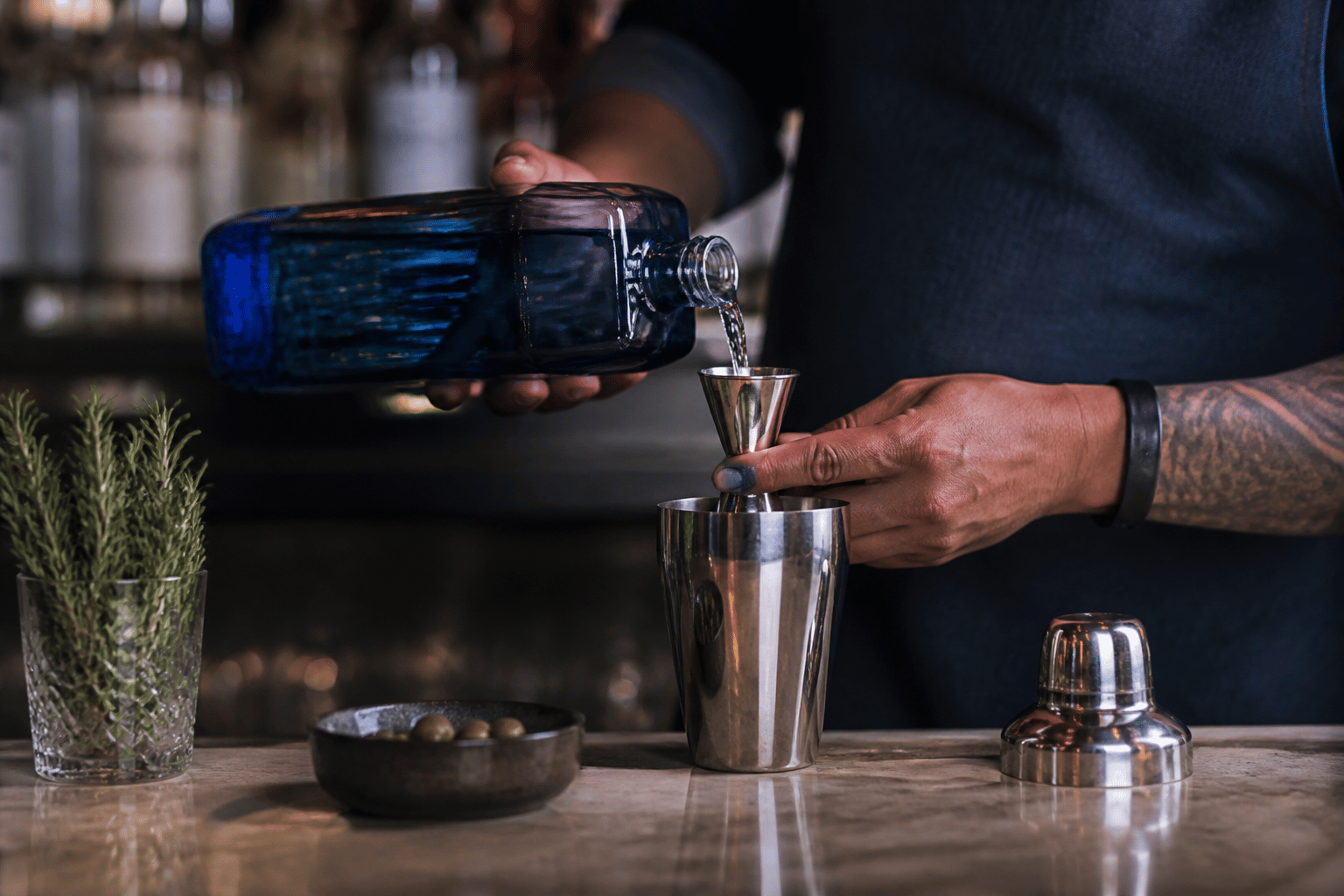 Bartender measuring a cocktail ingredient with a jigger at a professional bar